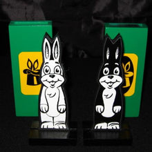 Two cartoon rabbit figures on stands with green bases featuring yellow logos.