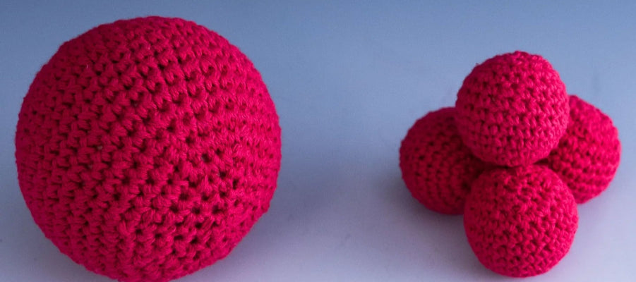 Three red crocheted balls on a gradient blue and white background