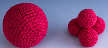 Three red crocheted balls on a gradient blue and white background