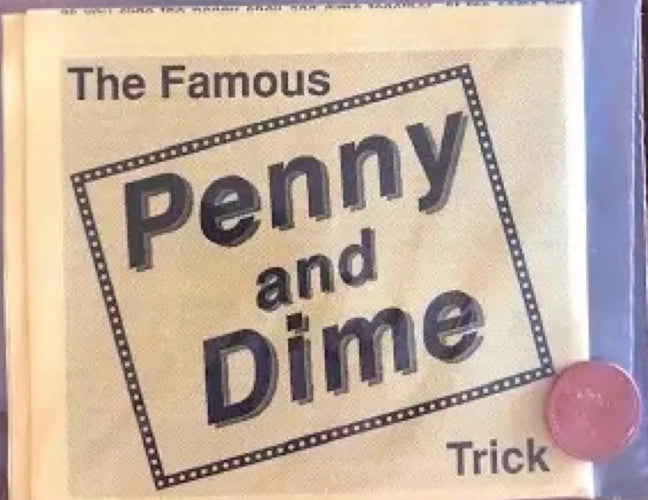 Book titled 'The Famous Penny and Dime Trick' with a pink button on a wooden surface.
