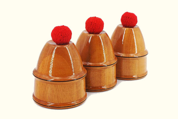 Three wooden cups with red balls on top on a white background