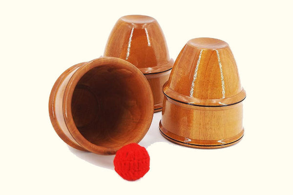 Wooden cups with a red ball on a white background