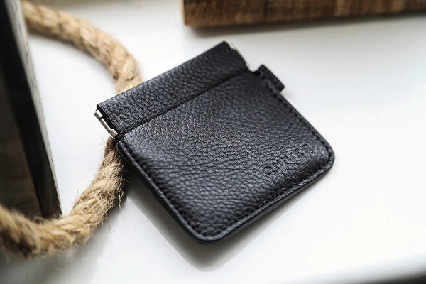 Black leather wallet on a light surface with a rope-like object.
