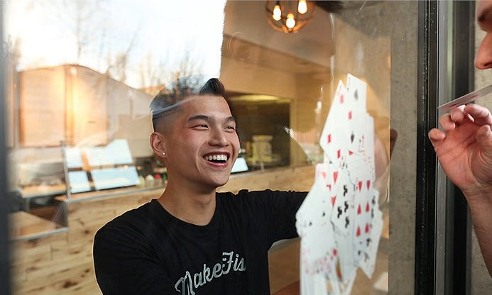 Person playing cards through a glass door with a casual indoor setting.