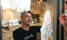Person playing cards through a glass door with a casual indoor setting.