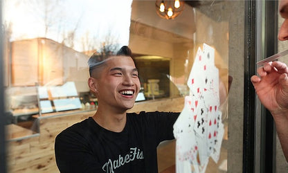 Person playing cards through a glass door with a casual indoor setting.