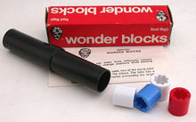 Black cylindrical container with wonder blocks and packaging on a white background