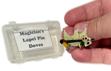 Magician's lapel pin with dove design held by a hand next to its packaging.