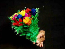 Colorful feathered object held by a hand against a black background