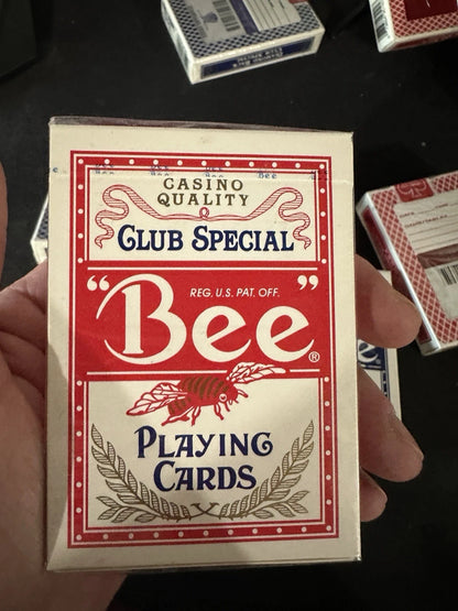 Box of Bee Club Special playing cards held by a hand on a dark background