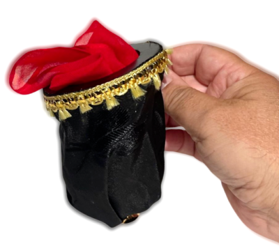 Black top hat with red interior and gold band held by a hand on a white background