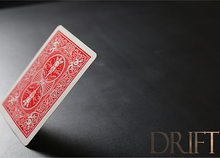 Red playing card on a dark surface with 'DRIFT' branding.