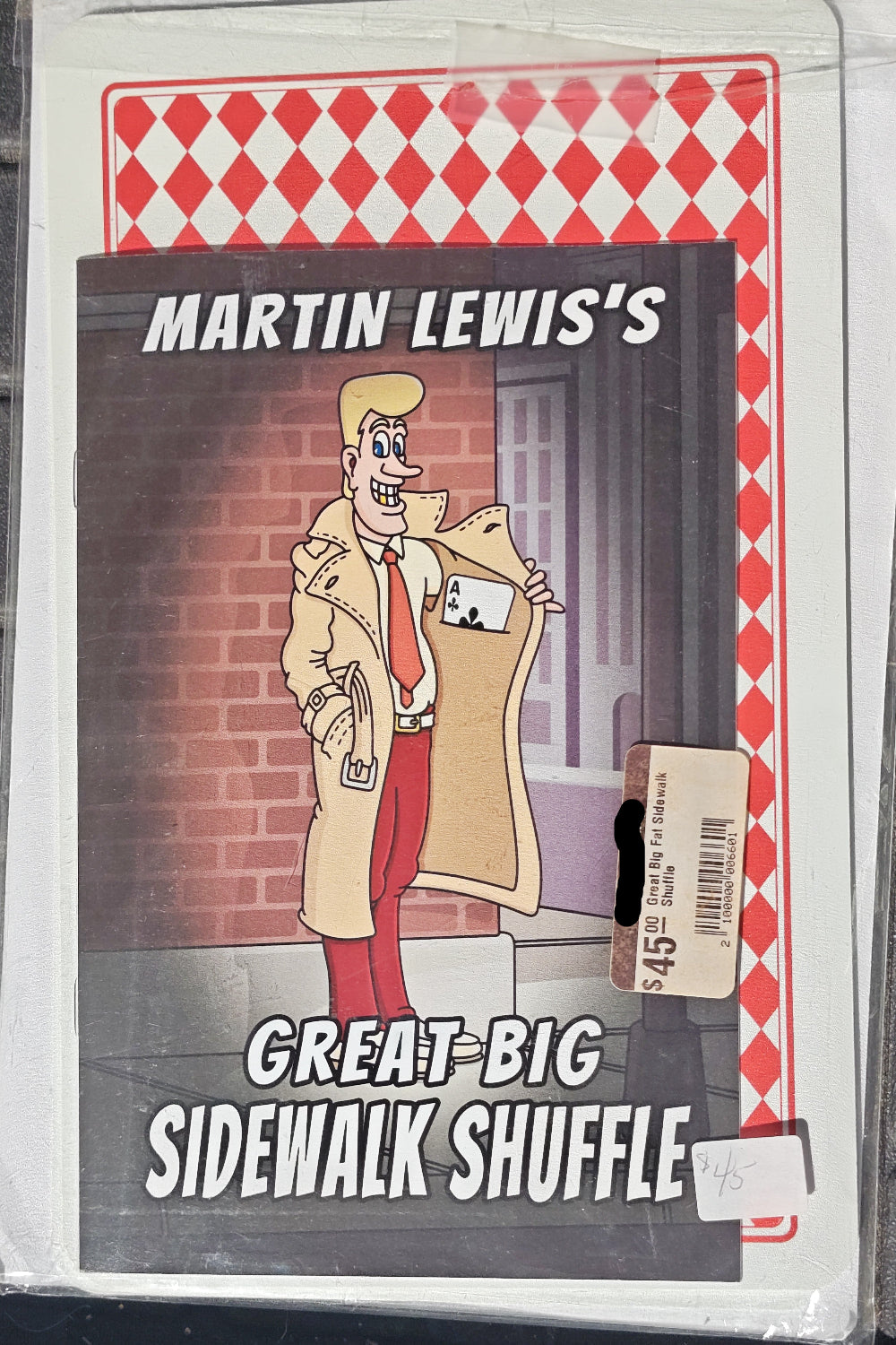 Cardboard box with a cartoon character and text 'Martin Lewis's Great Big Sidewalk Shuffle' on a red and white checkered background.