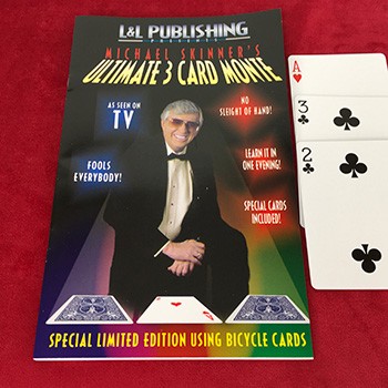 Magical trick book with a magician on the cover and playing cards beside it on a red background