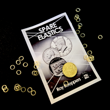 Packaging of spare elastics with coins on a black background