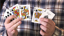 Two hands holding playing cards against a plaid shirt background