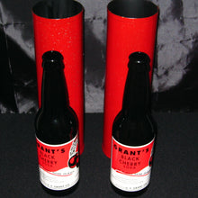 Two bottles of Grant's Black Cherry Soda with red labels and red cardboard stands on a dark surface.