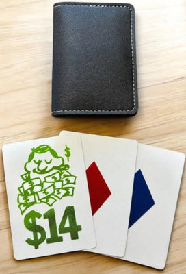 Black wallet and playing cards with a green character and '$14' on a wooden surface