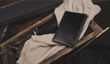 Black leather wallet on a wooden surface with a blurred background